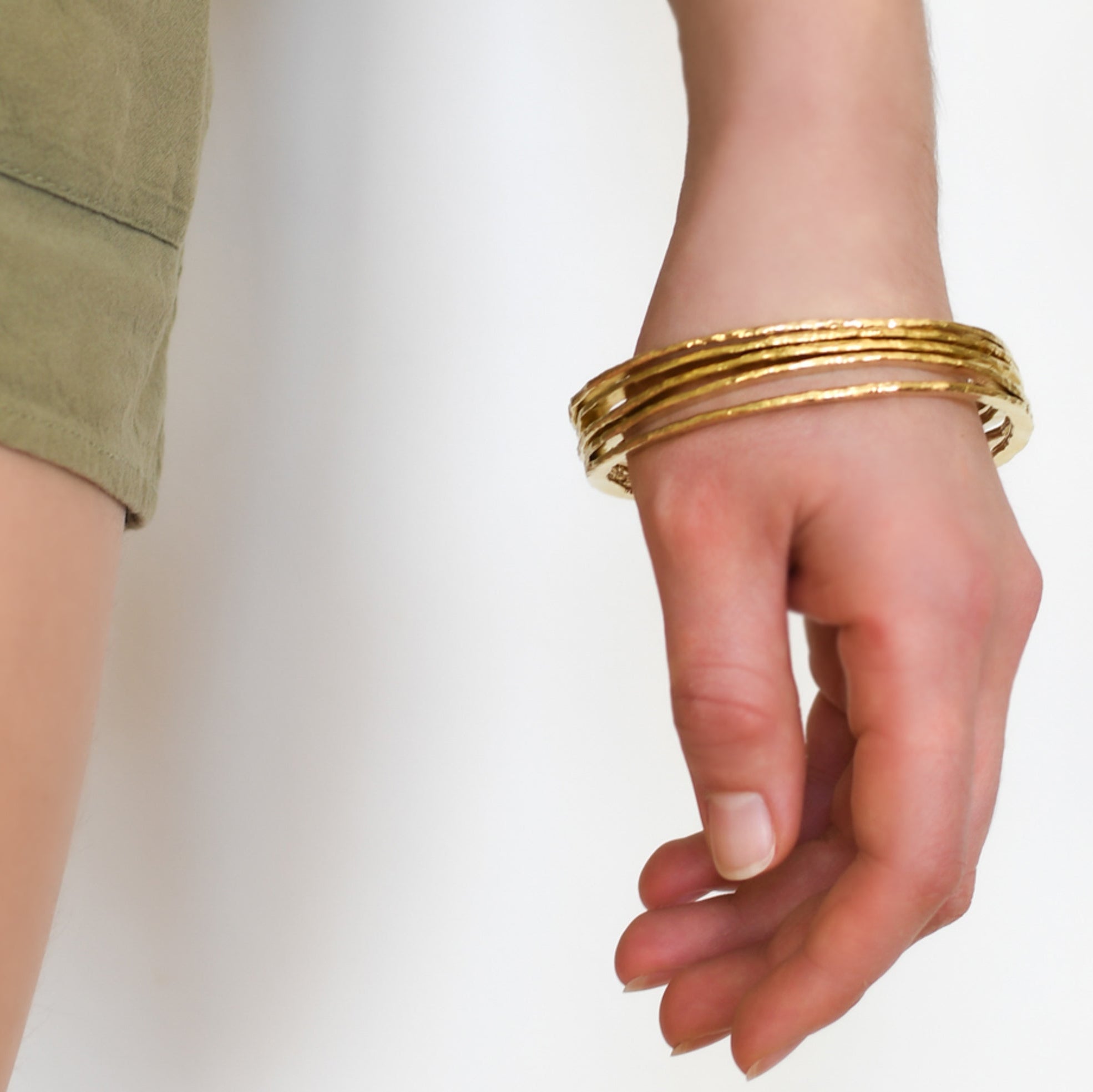 Hand wearing gold bracelets on a white background